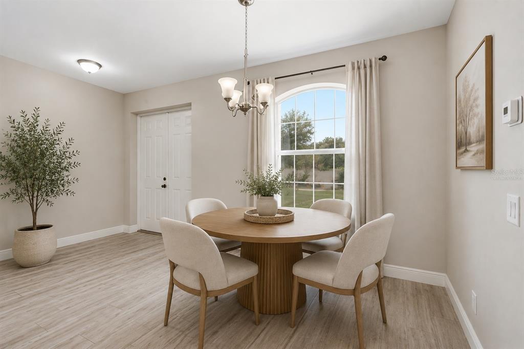 A dining area features a round wooden table, four chairs, and a large arched window — 3498 DUNKIRK STREET, PORT CHARLOTTE, FL