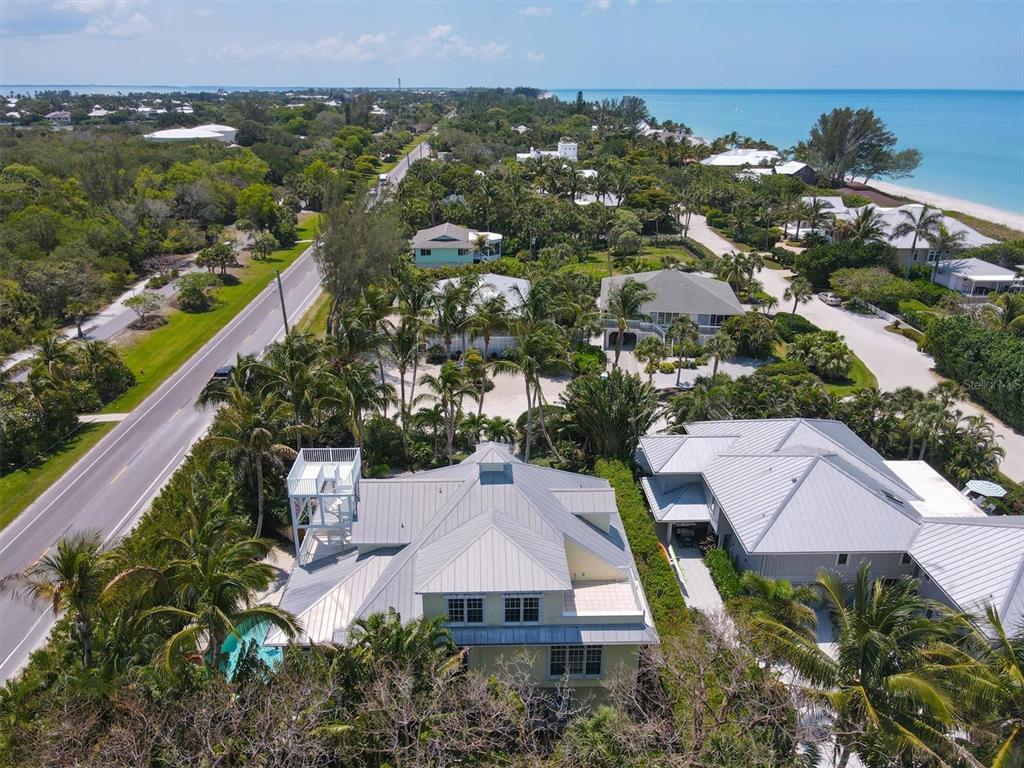An aerial view shows a coastal house with a metal roof near a road and beach — 2425 24TH STREET W, BOCA GRANDE, FL