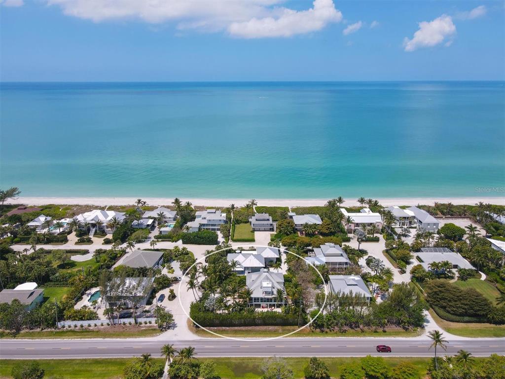 An aerial view shows a beachfront house surrounded by palm trees near a coastal road — 2425 24TH STREET W, BOCA GRANDE, FL