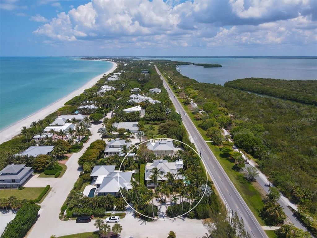 An aerial view shows a coastal residential property surrounded by palm trees near a beach — 2425 24TH STREET W, BOCA GRANDE, FL
