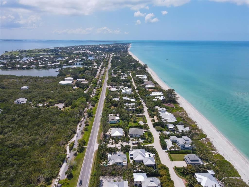 An aerial view shows a coastal road separating a dense forest from beachfront residential homes — 2425 24TH STREET W, BOCA GRANDE, FL