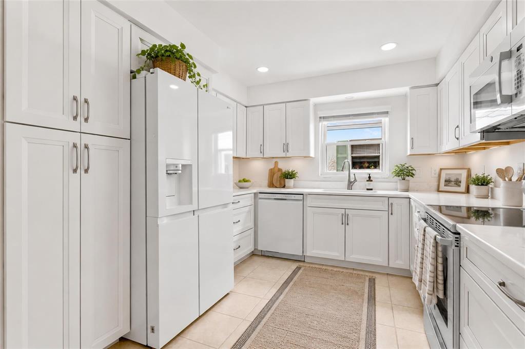 A white kitchen features shaker-style cabinets, stainless steel appliances, and a beige tiled floor — 3271 MCMATH DRIVE, PALM HARBOR, FL
