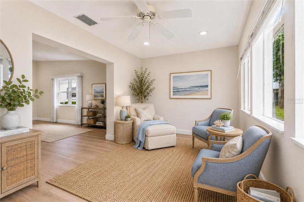 A sunroom features light wood flooring, a jute rug, blue armchairs, and a beige chaise — 3271 MCMATH DRIVE, PALM HARBOR, FL