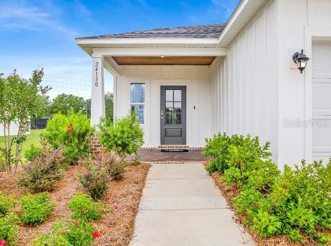 The exterior of a white house features a covered front porch and a dark door — 28 WOOD ACRE LANE, PALM COAST, FL