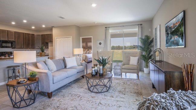 A living room with a gray sofa, two armchairs, and an open kitchen in the background — 28 WOOD ACRE LANE, PALM COAST, FL