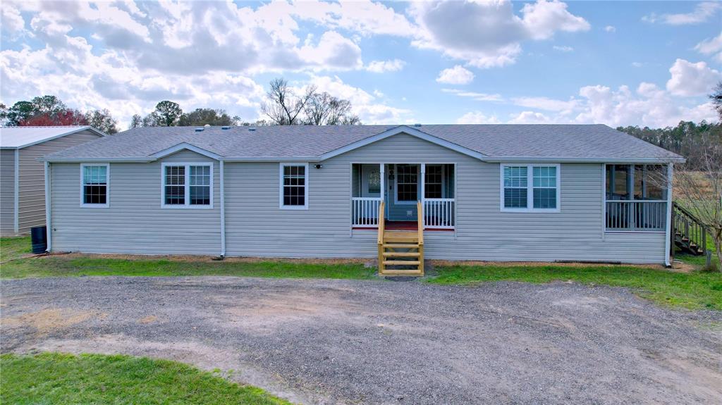 A light gray manufactured home features a front porch with wooden stairs and a driveway — 14890 CR 757, WEBSTER, FL