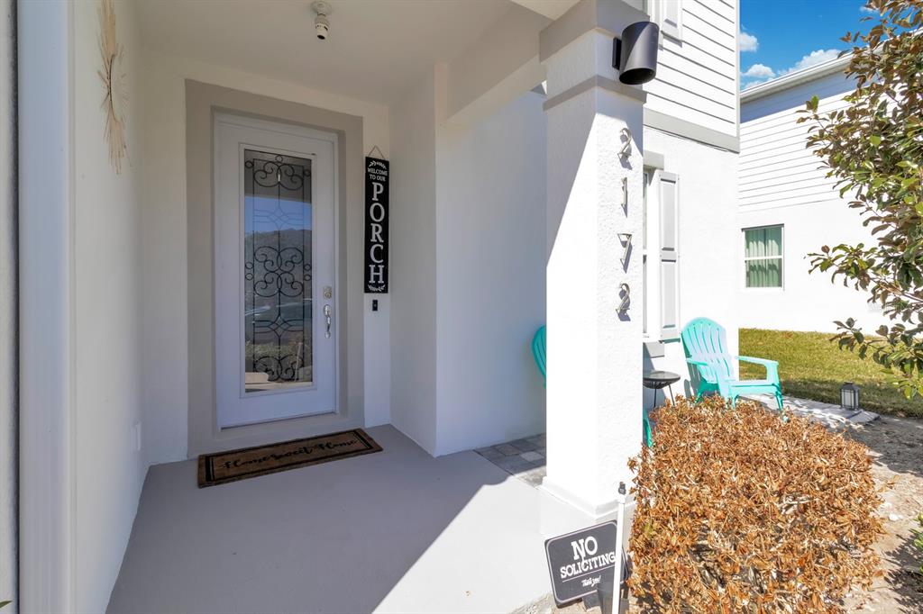 A front porch features a white door with a glass insert, chairs, and a house number — 2172 BUR OAK BOULEVARD, ST CLOUD, FL
