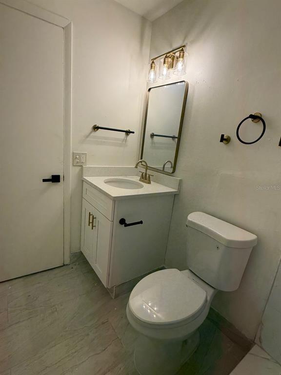 A bathroom features a white vanity, a gold-framed mirror, and a white toilet — 2711 WILLOW RUN, ORLANDO, FL