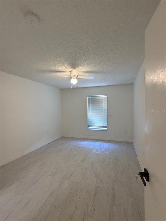 An empty bedroom features white walls, light-colored tile flooring, a ceiling fan, and a window — 2711 WILLOW RUN, ORLANDO, FL