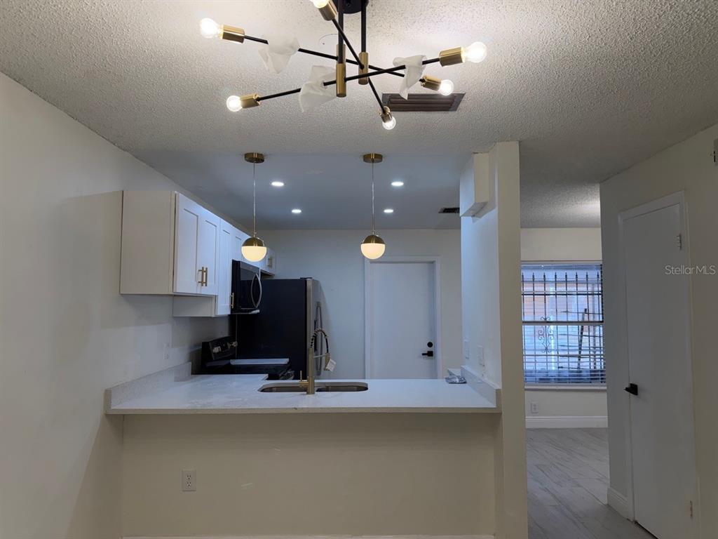 A kitchen with white cabinets, a breakfast bar, and a modern chandelier above the dining area — 2711 WILLOW RUN, ORLANDO, FL