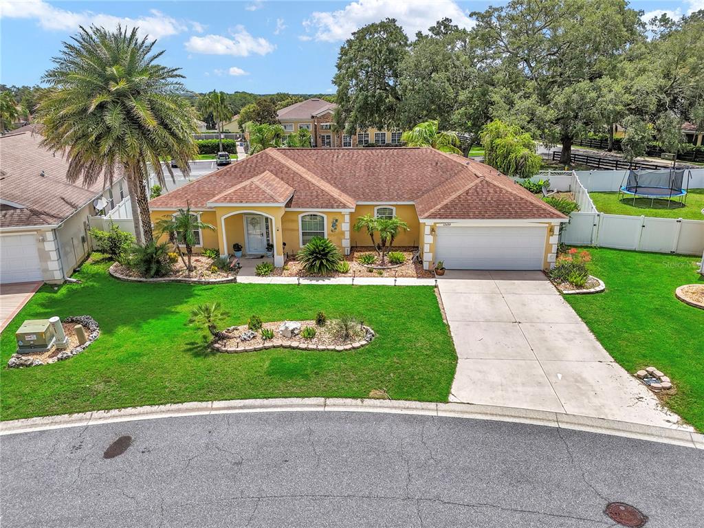 An aerial view of a single-story yellow house with a brown roof and driveway — 12439 NE 48TH CIRCLE, OXFORD, FL
