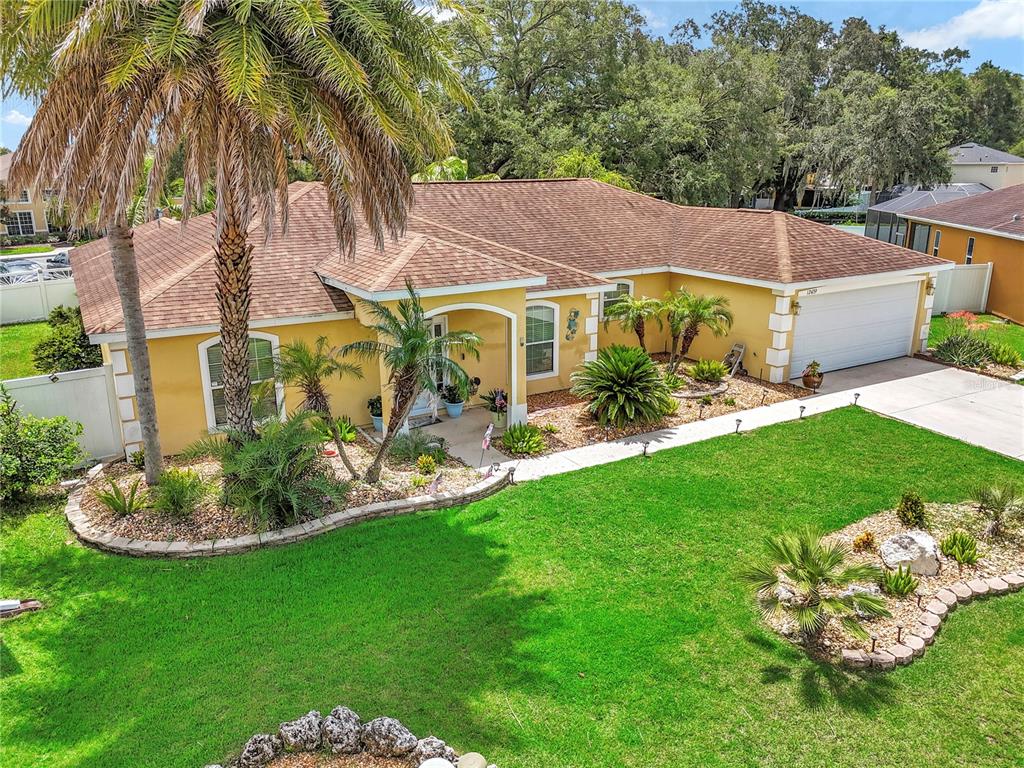 An aerial view of a yellow single-story house with a palm tree and landscaped yard — 12439 NE 48TH CIRCLE, OXFORD, FL