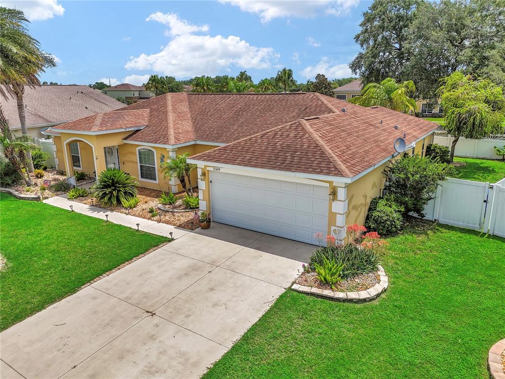 An aerial view of a single-story house with a tan exterior, brown roof, and driveway — 12439 NE 48TH CIRCLE, OXFORD, FL