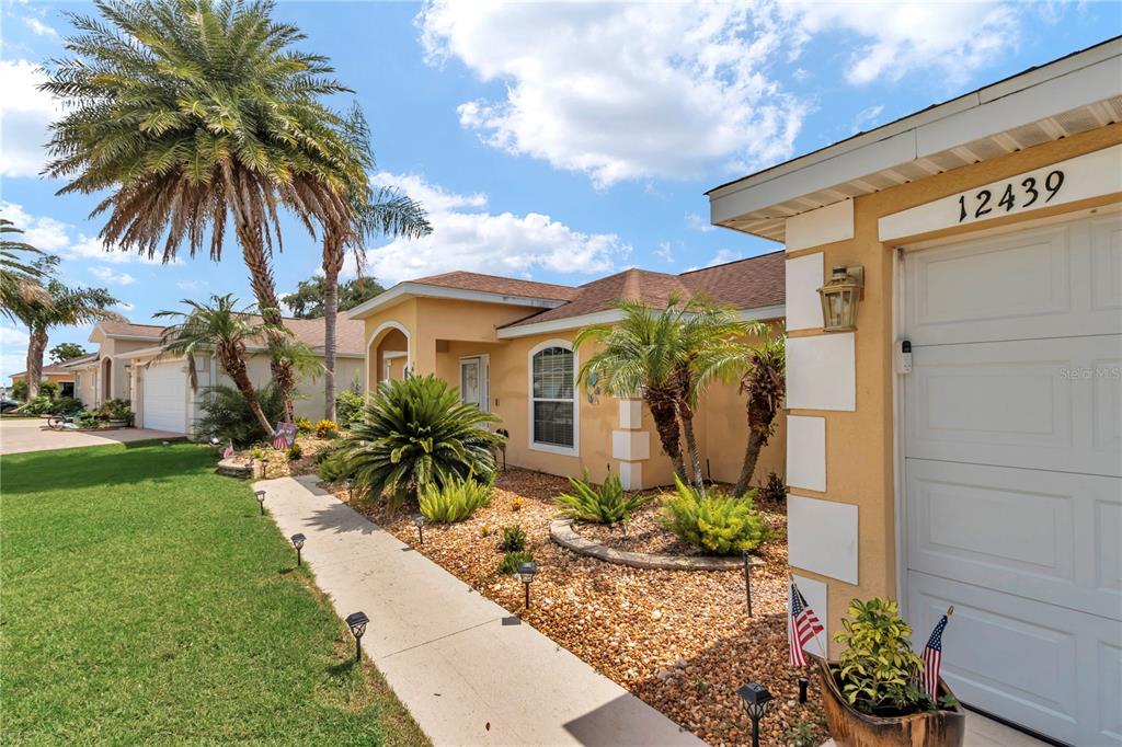 A single-story house exterior features a tan stucco facade, a garage, and a landscaped yard — 12439 NE 48TH CIRCLE, OXFORD, FL