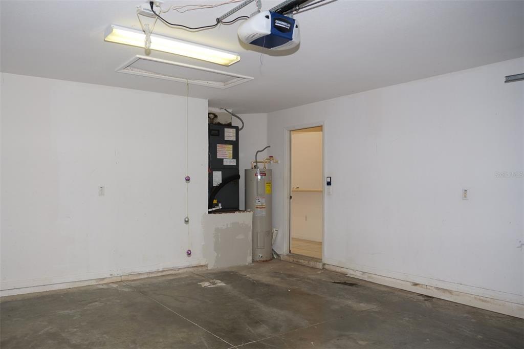 A garage interior features a water heater, HVAC unit, and a ceiling-mounted garage door opener — 969 ANDALUSIA LOOP, DAVENPORT, FL