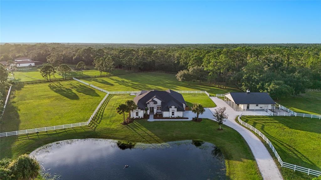 An aerial view shows a house and detached garage on a large, fenced rural lot — 7310 201ST STREET E, BRADENTON, FL