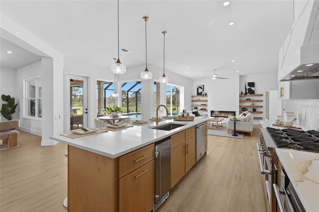 A modern kitchen with light wood cabinets and a white island overlooks an open living area — 7310 201ST STREET E, BRADENTON, FL