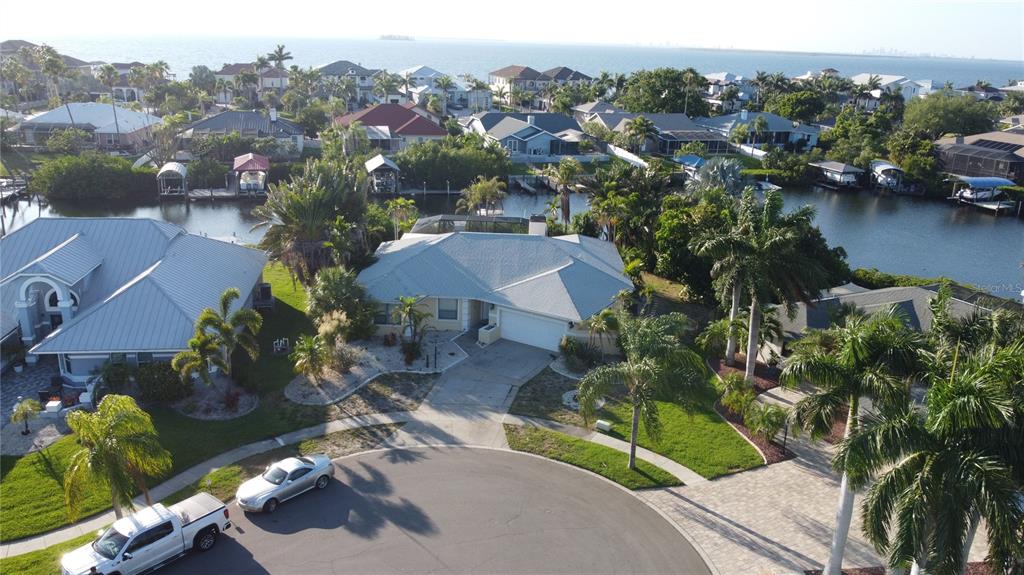 An aerial view shows a suburban house with a metal roof near a canal — 6612 BLACKFIN WAY, APOLLO BEACH, FL