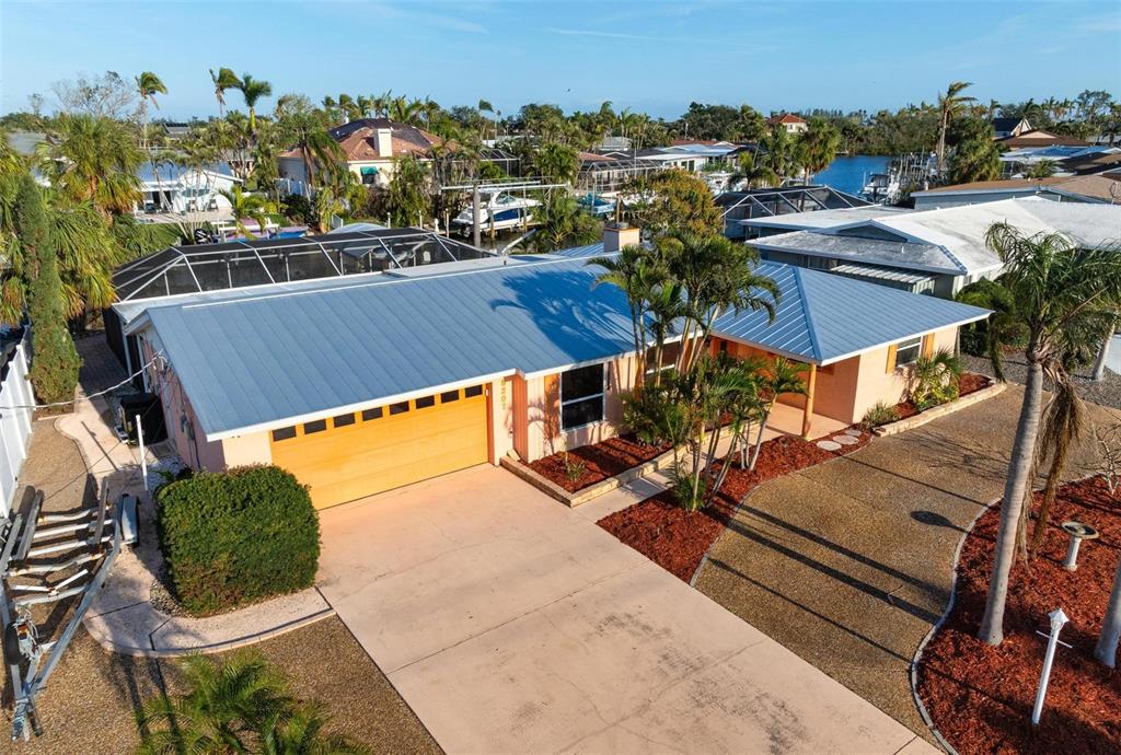 An aerial view of a single-story house with a metal roof and a concrete driveway — 5207 BIMINI DRIVE, BRADENTON, FL