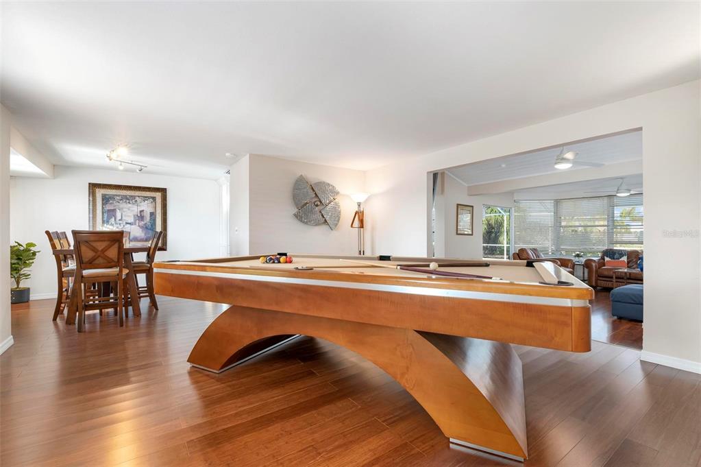 A pool table sits on a wood floor in a room with an adjacent dining area — 5207 BIMINI DRIVE, BRADENTON, FL