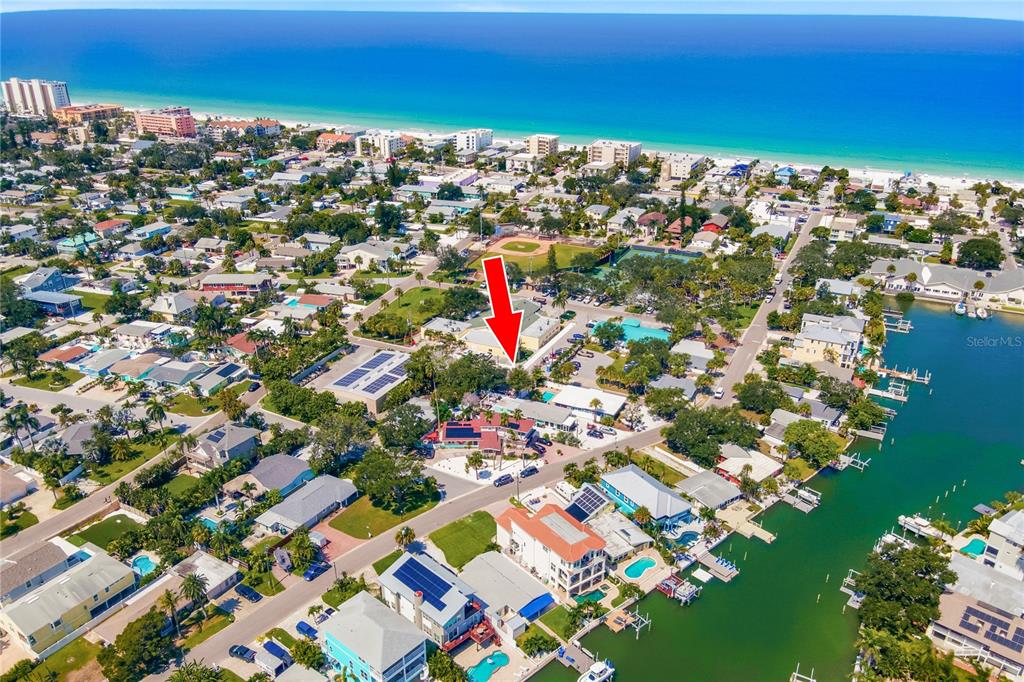 An aerial view shows a coastal neighborhood with houses, a canal, and a red arrow — 1509 LEGION LANE, INDIAN ROCKS BEACH, FL