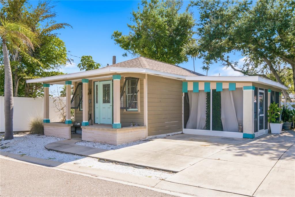 A tan single-story house features a front porch, a screened-in patio, and a concrete driveway — 1509 LEGION LANE, INDIAN ROCKS BEACH, FL