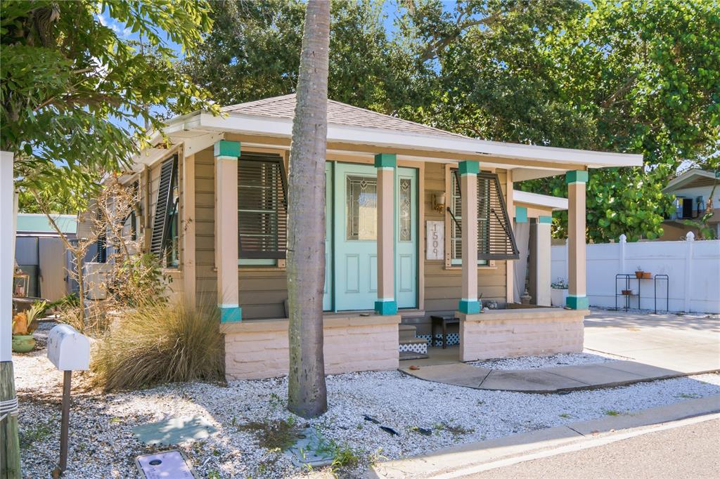 A small, tan cottage with a light blue front door and a covered front porch — 1509 LEGION LANE, INDIAN ROCKS BEACH, FL