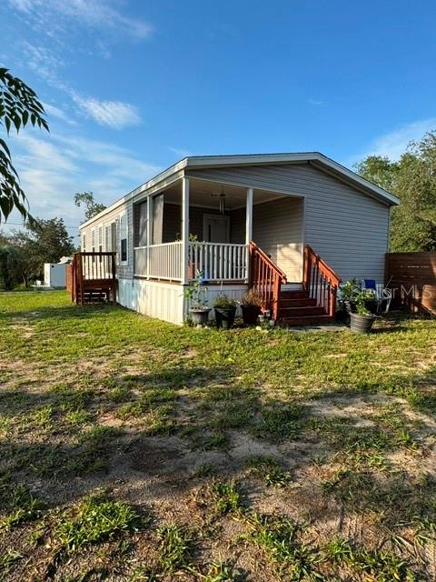 A single-story mobile home with a front porch and wooden stairs sits on a grassy lot — 8314 EVERGREEN AVENUE, BROOKSVILLE, FL