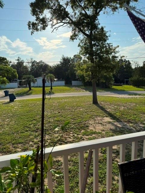 A view of a grassy yard and trees from a white porch railing — 8314 EVERGREEN AVENUE, BROOKSVILLE, FL