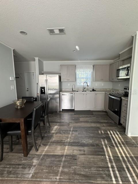 A kitchen features light gray cabinetry, stainless steel appliances, and wood-look flooring — 8314 EVERGREEN AVENUE, BROOKSVILLE, FL