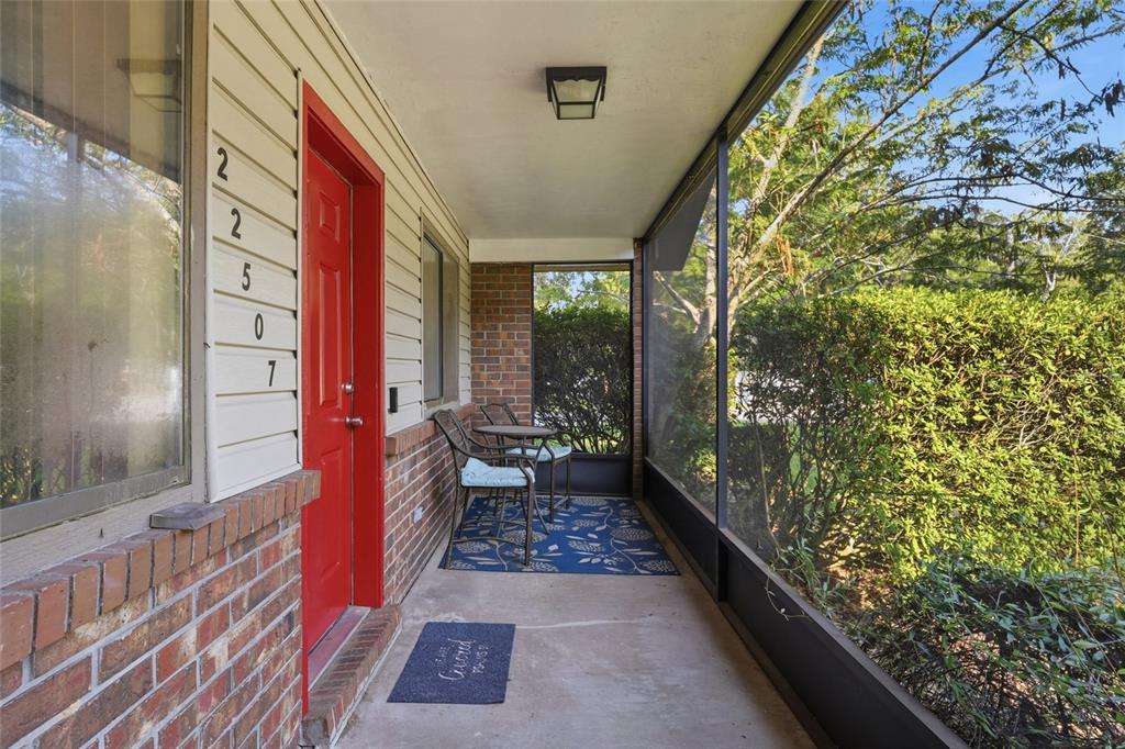 A screened-in porch features a red front door, brick accents, and a blue patterned rug — 22507 NW 176TH PLACE, HIGH SPRINGS, FL