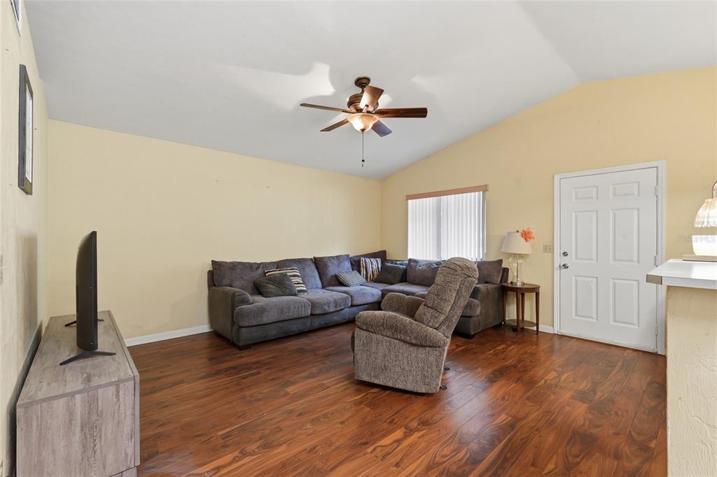 A living room features a gray sectional sofa, a recliner, and wood-look flooring — 22507 NW 176TH PLACE, HIGH SPRINGS, FL