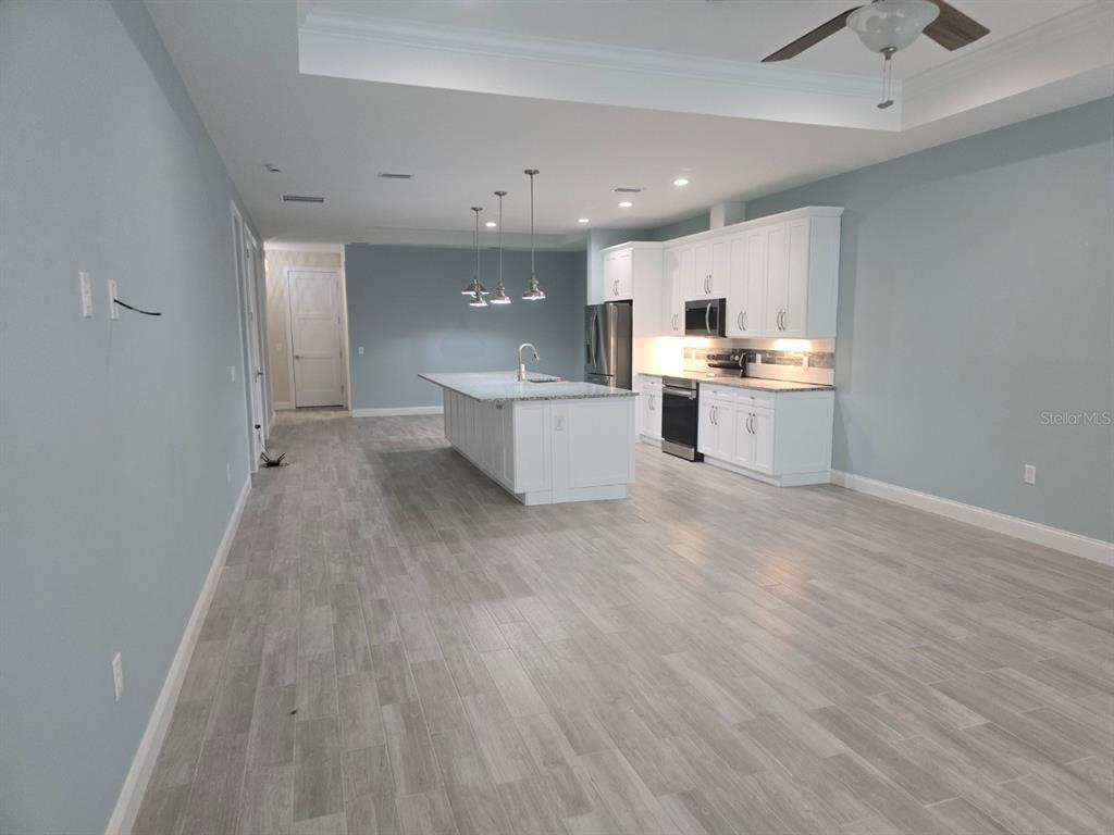 A kitchen features white cabinets, a central island, and light-colored wood-look tile flooring — 127 ULLIAN TRAIL UNIT B, PALM COAST, FL