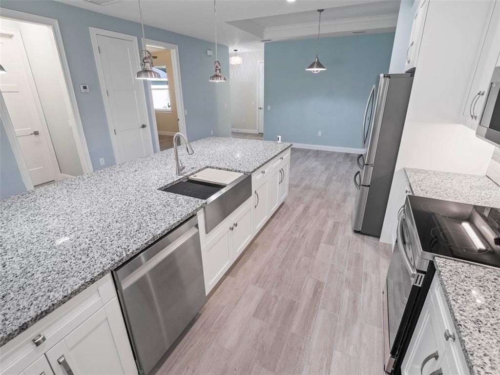 A kitchen features white cabinets, granite countertops, stainless steel appliances, and light blue walls — 127 ULLIAN TRAIL UNIT B, PALM COAST, FL