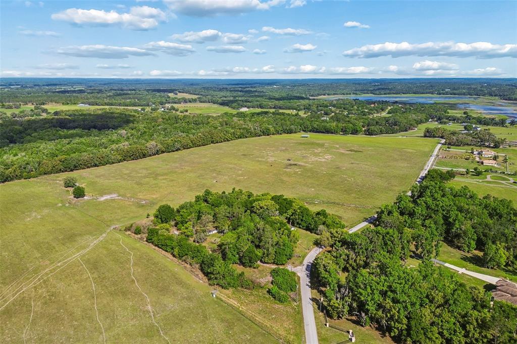 An aerial view shows a large, open grassy field bordered by trees and a road — BAYHEAD ROAD Lot 6-9, DADE CITY, FL