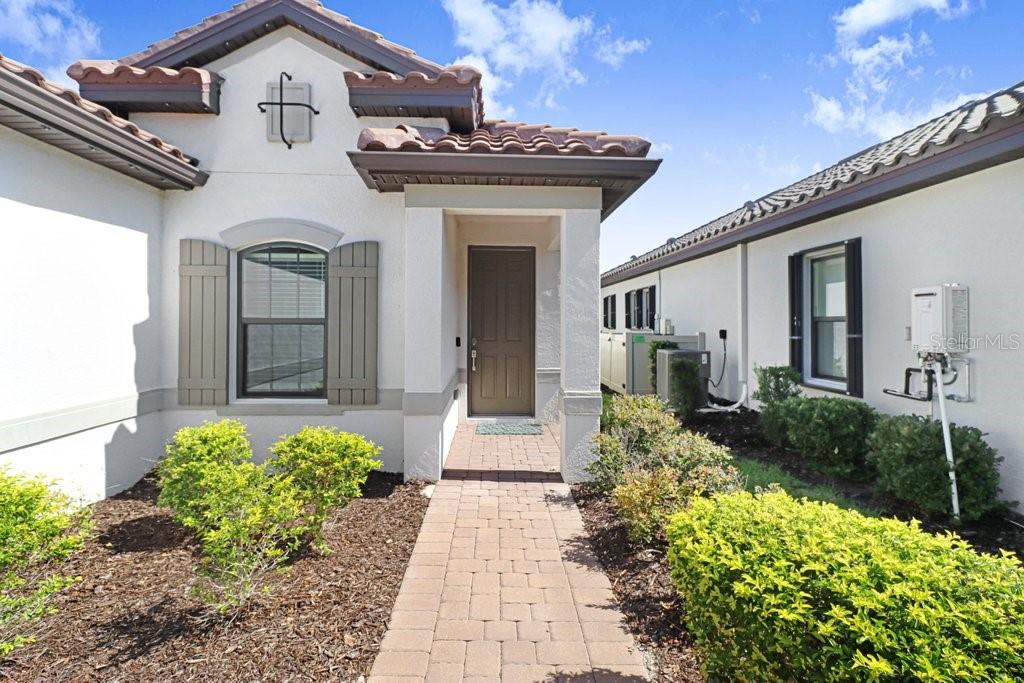 A paved walkway leads to the front entrance of a house with a tiled roof — 4634 CRESTPOINT WAY, PALMETTO, FL