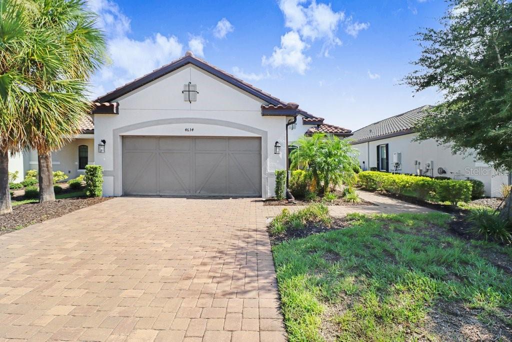 A single-story house with a beige stucco exterior, a tiled roof, and a paved driveway — 4634 CRESTPOINT WAY, PALMETTO, FL