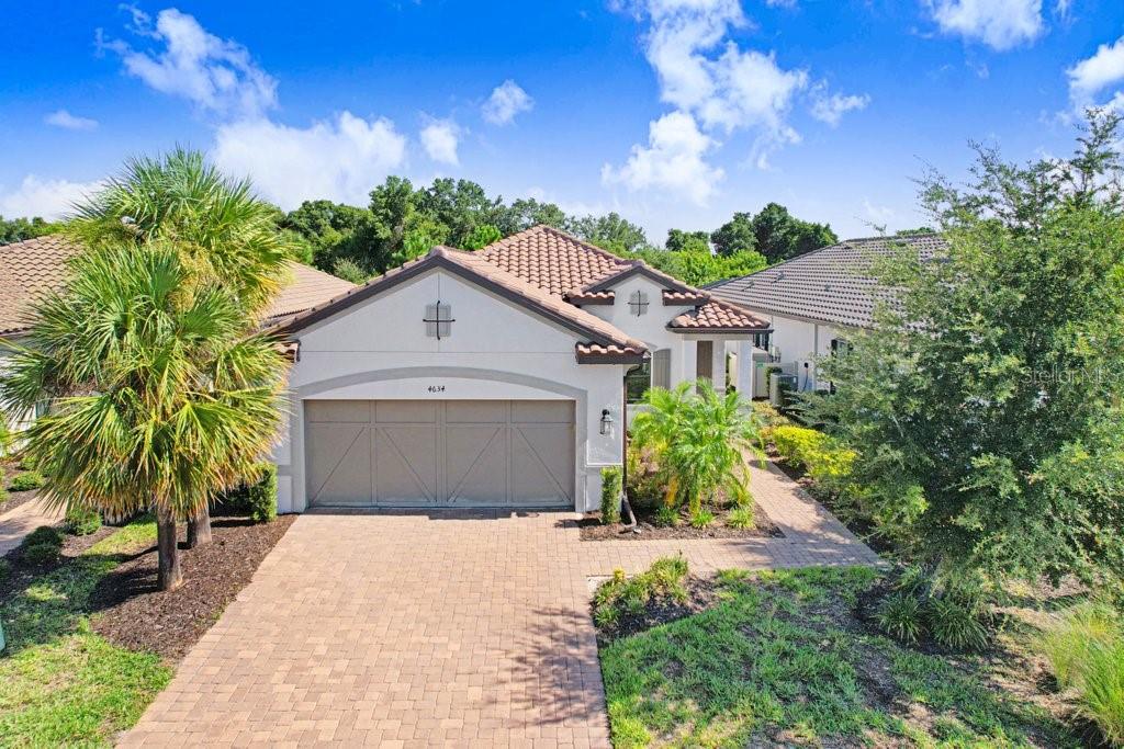 A single-story house with a beige stucco exterior, a tiled roof, and a paved driveway — 4634 CRESTPOINT WAY, PALMETTO, FL