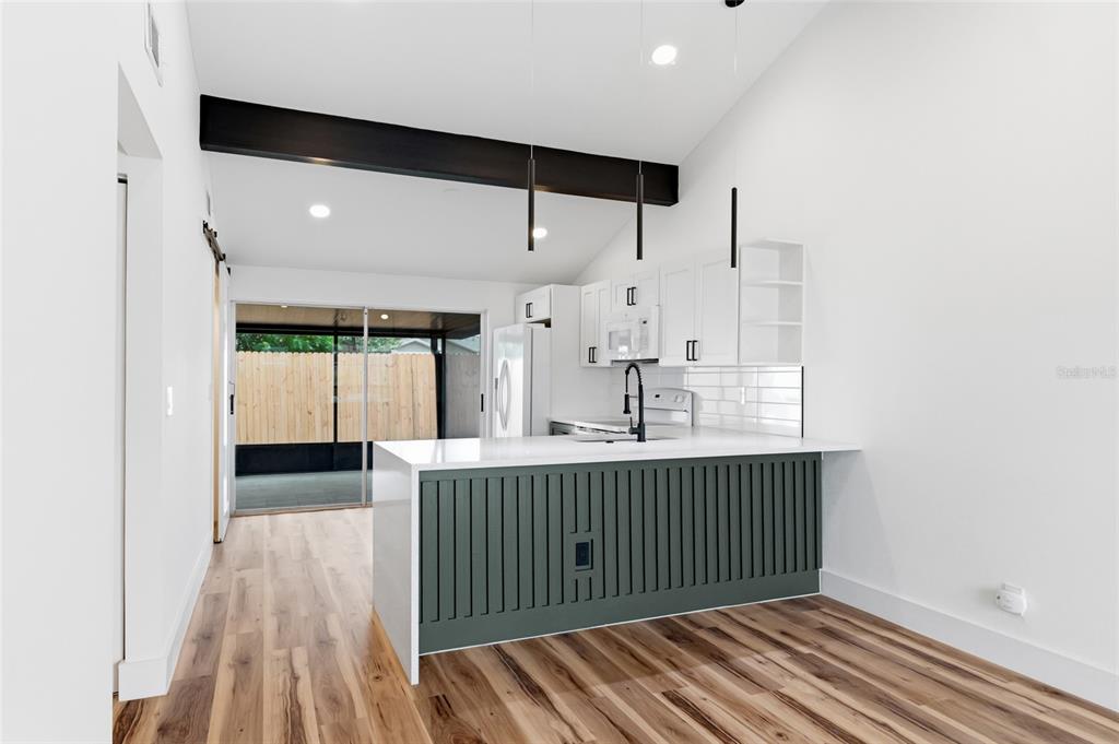 A kitchen with white upper cabinets, dark lower cabinets, white appliances, and exposed black beams — 8602 BRIAR GROVE CIR, TAMPA, FL
