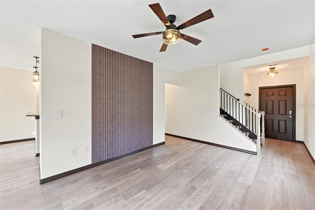 A living room features wood-look flooring, a slatted wood accent wall, and a ceiling fan — 1403 TRAILWATER STREET, RUSKIN, FL
