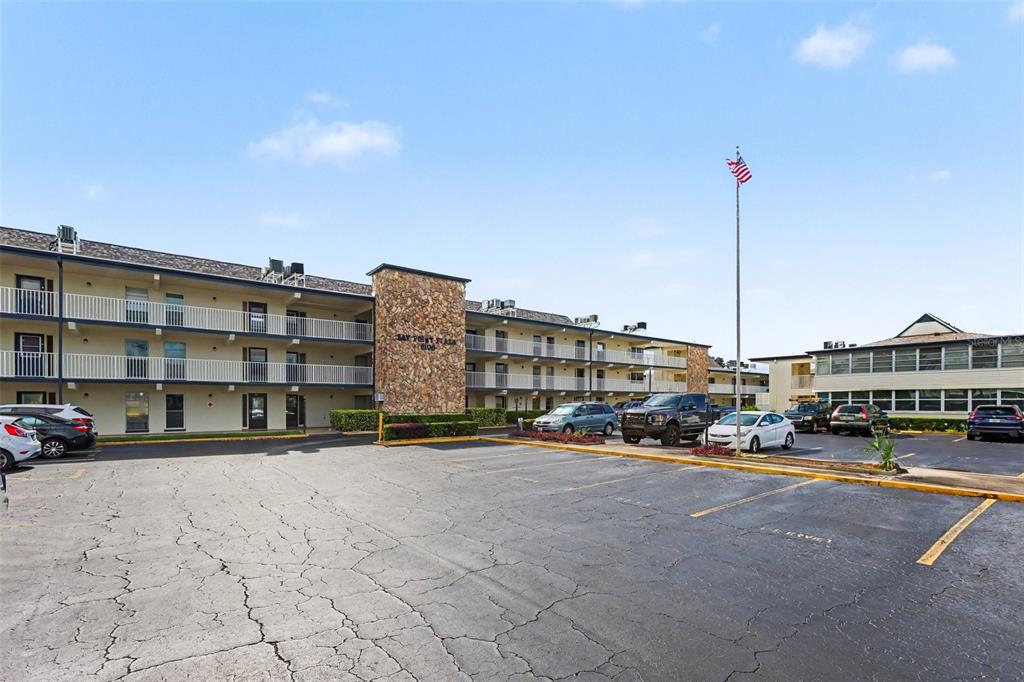 A multi-story apartment building with a stone facade and parking lot under a blue sky — 6100 12TH STREET S UNIT 313, ST PETERSBURG, FL