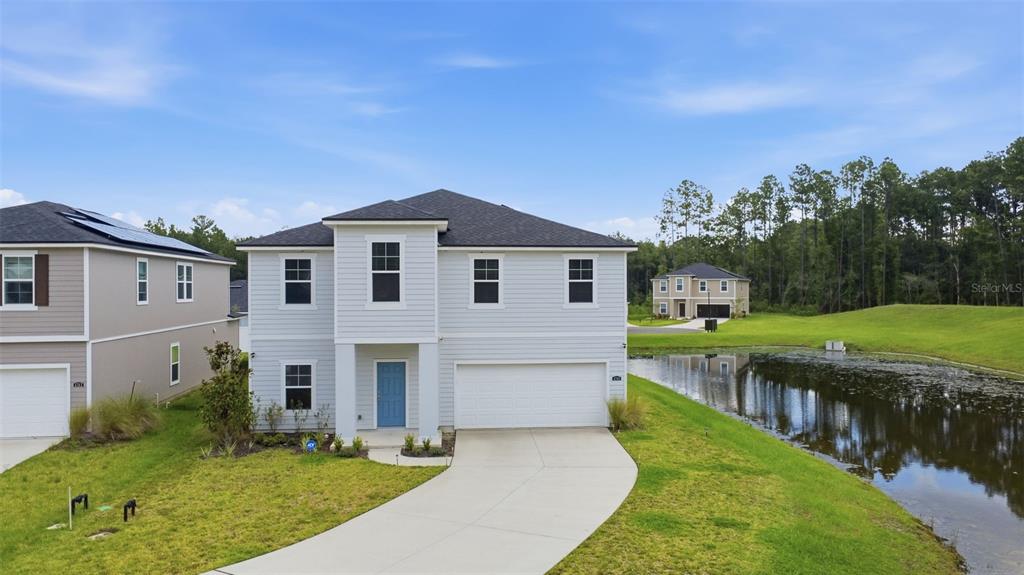 A two-story light gray house with a blue front door sits beside a small pond — 4768 ARGAND DRIVE, JACKSONVILLE, FL