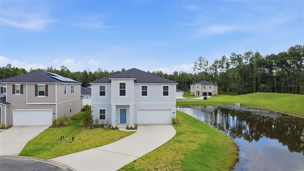 A two-story house with light siding and a two-car garage sits beside a pond — 4768 ARGAND DRIVE, JACKSONVILLE, FL