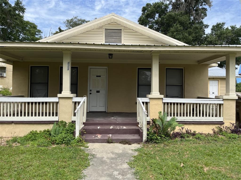 A single-story house with a front porch and a water tower in the background — 818 NE 9TH AVENUE, OCALA, FL