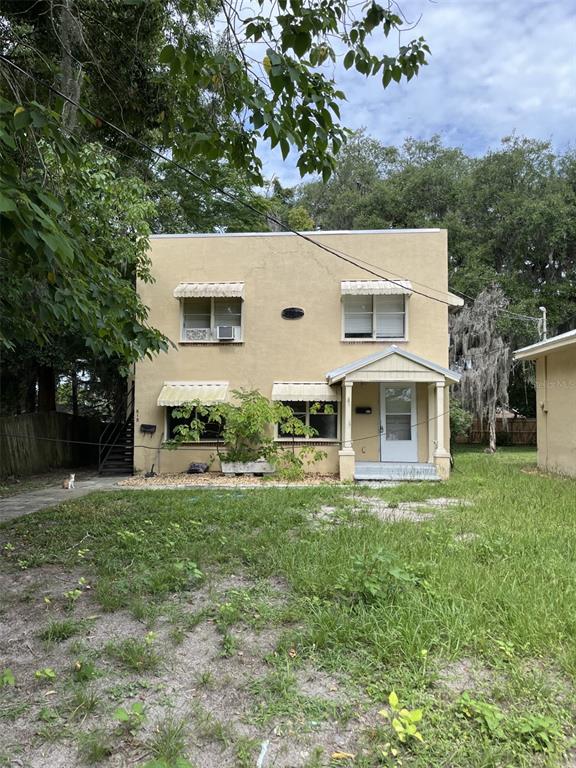 A single-story house with a yellow exterior, a front porch, and a concrete driveway — 818 NE 9TH AVENUE, OCALA, FL