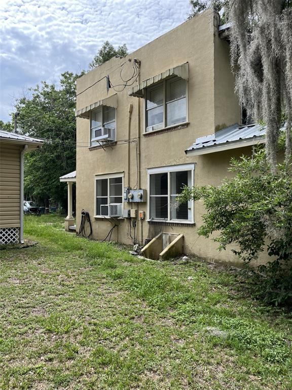 A two-story tan stucco house with a small front porch stands in a grassy yard — 818 NE 9TH AVENUE, OCALA, FL