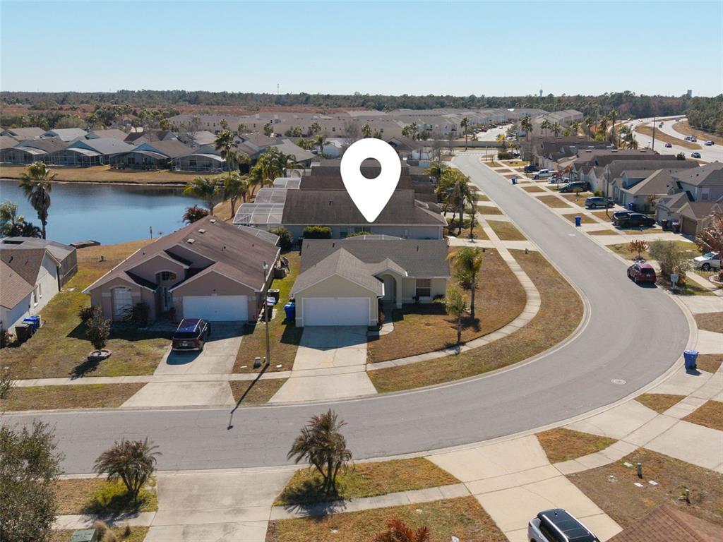 An aerial view shows a suburban neighborhood with houses, a lake, and a curved road — 1043 SOARING EAGLE LANE, KISSIMMEE, FL