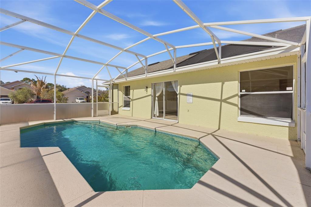 A swimming pool sits on a concrete patio enclosed by a white metal screen cage — 1043 SOARING EAGLE LANE, KISSIMMEE, FL