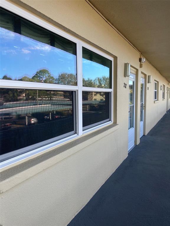 An exterior view of a building corridor with a large window and apartment unit doors — 5750 80TH STREET N UNIT C202, ST PETERSBURG, FL