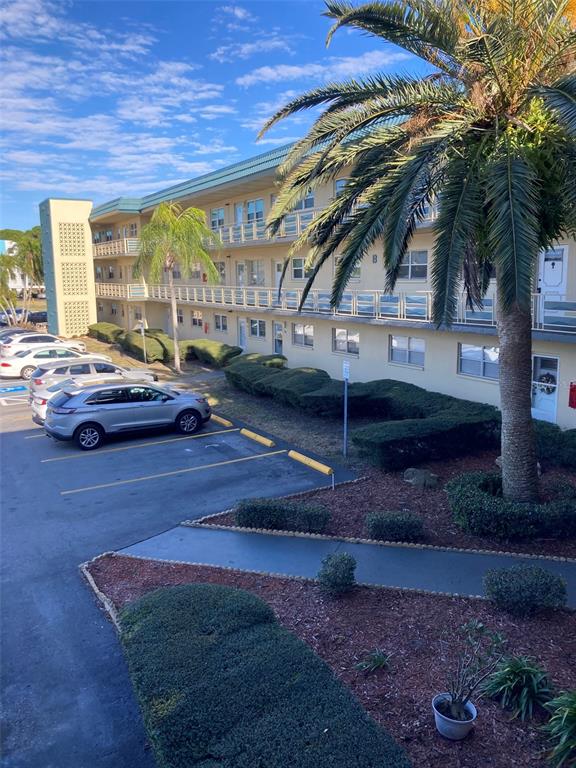 An exterior view of a multi-story apartment building with a parking lot and palm trees — 5750 80TH STREET N UNIT C202, ST PETERSBURG, FL